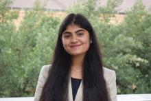 An image of a young lady in a beige blazer smiling. 